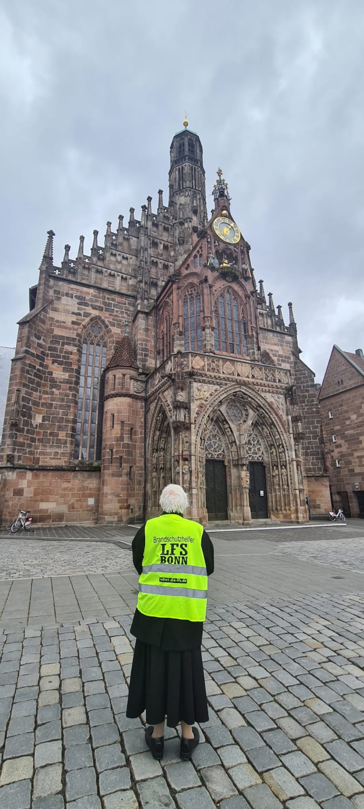Person mit Sicherheitsweste mit Aufdruck "Brandschutzhelfer LFS Bonn" vor der Liebfrauenkirche in Nürnberg.