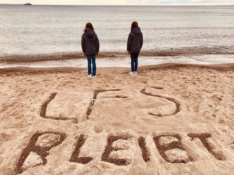 Zwei Mädchen am Strand davor im Sand die Schrift LFS bleibt