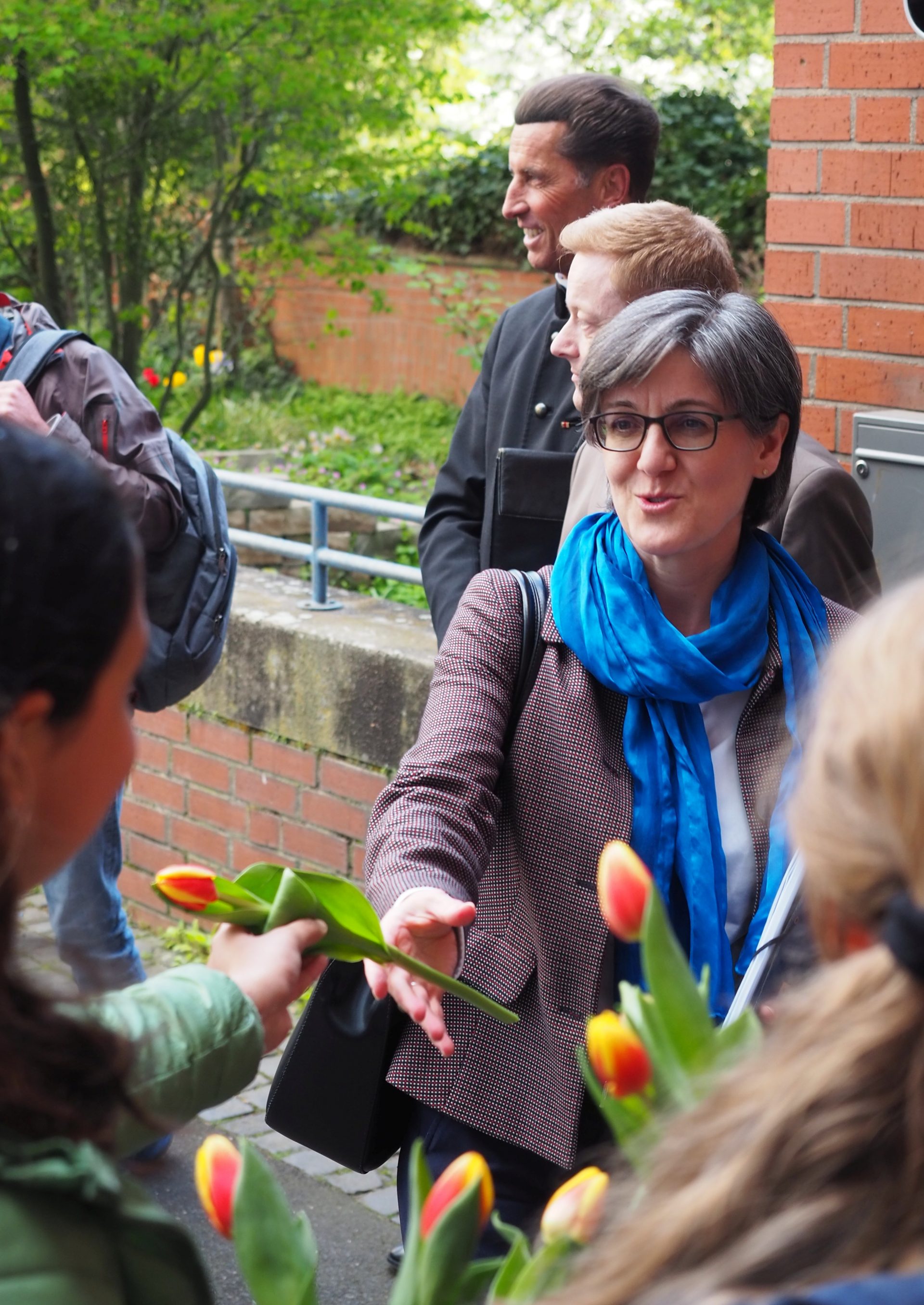 Schülerinnen übergeben eine Blume an Frau Dr. Schwarz-Boenneke